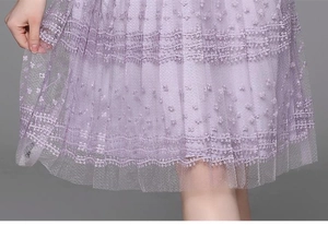 Detailed close-up of purple lace embroidery and lightweight mesh fabric on the dress hem