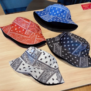 Flat lay of four paisley cotton bucket hats in red blue black and white colors on wood