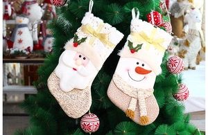 Detail of 3D Santa and Snowman Christmas stockings hanging on a green tree branch