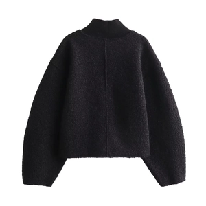 Close-up of black textured boucle knit fabric on a loose fit high-collar sweater jacket