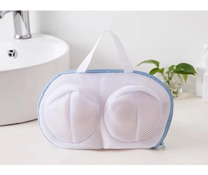 Detail of white mesh bra laundry bag with blue trim on bathroom counter