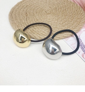 Close-up of minimalist gold and silver metallic bean charms on elastic hair ties