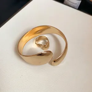 Polished gold oval open cuff bracelet and matching ring set with minimalist smooth finish