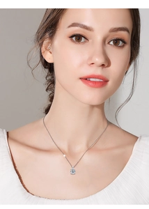 Close-up of a 1 carat round moissanite pendant necklace on a silver chain worn by a model