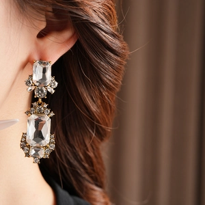 Macro detail of vintage square gold earrings featuring clear crystal embellishments