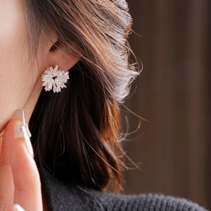 Gros plan de boucles d'oreilles fleurs en perles et cristaux portées pour un look luxe