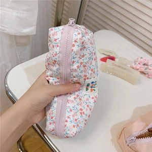 Close-up of floral cotton stationery bag with a purple zipper and delicate fabric label
