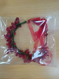 Detail view of a red floral sunflower wreath with artificial flowers and mesh ribbon in a bag