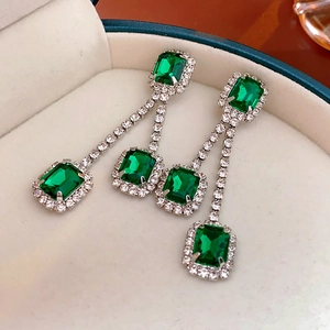 Macro view of emerald-cut green gemstone earrings with tassels in a jewelry box