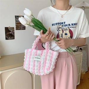 Close-up of seersucker tote bag with quilted texture and brand label in pink and white