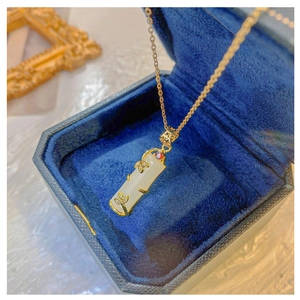 Detail of white jade bamboo pendant with 18k gold leaves and ruby on blue velvet