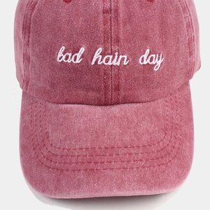 Vintage red washed cotton baseball cap with Bad Hair Day embroidery on white background