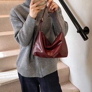 Retro burgundy large capacity tote bag in glossy leather worn with a grey sweater