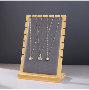 Detailed side view of bamboo necklace display stand with gray velvet padding and slots