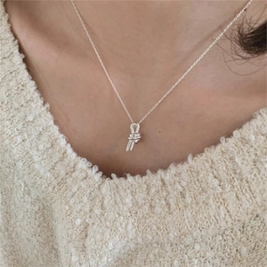 Close-up of a 925 sterling silver knot pendant necklace worn on a soft knit sweater