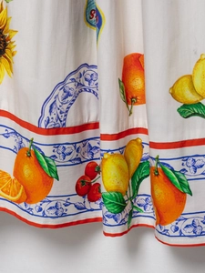Detail von mediterranem Zitrus- und Blumendruck mit blauem Fliesenmuster am Kleid