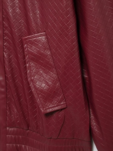 Detailed macro view of woven faux leather texture on a burgundy oversized bomber jacket