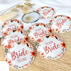 Wedding tinplate badges featuring Team Bride floral designs on a rustic wooden surface