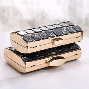 Detail of luxury acrylic evening clutch bag with marble texture and gold metal frame
