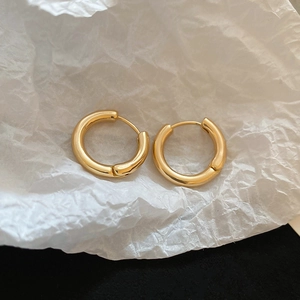 Detailed view of polished gold hoop earrings featuring a minimalist and smooth circular design
