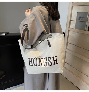 Close-up of large canvas tote bag with leather handles and HONGSH letter printing