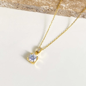Macro detail of gold four-claw pendant with sparkling round cubic zirconia stone