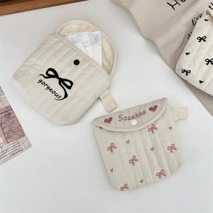 Close-up of quilted storage pouches with ribbon embroidery and snap button closure