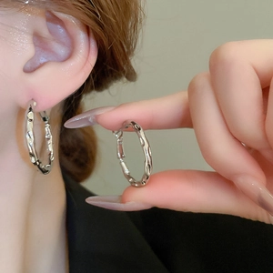 Detailed close-up of irregular lava texture on silver-colored geometric hoop earrings