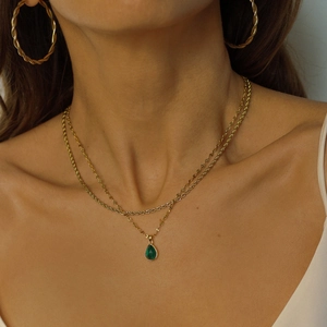 Double-layered gold necklace with green drop pendant and twisted hoop earrings on model