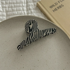 Detailed close-up of zebra print acetate hair claw with Bonjour France gold lettering