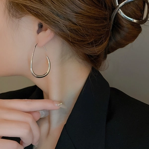 Close-up of polished silver teardrop earrings on model with high-shine metallic finish