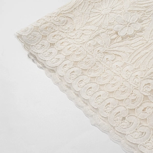 Close-up of ivory floral lace embroidery detailing on premium fabric surface