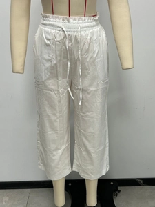 Detailed view of white linen wide-leg pants showing elastic high waist with drawstring
