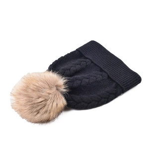 Close-up of black cable knit pattern and fluffy faux fur pompom on thermal winter beanie
