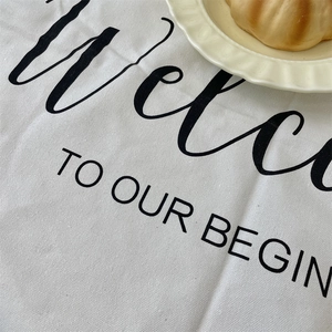 Close-up of white linen placemat with black art lettering and cream wavy ceramic plate