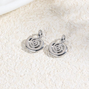 Close-up of silver spiral pendants for DIY jewelry making on a textured background