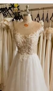 Detailed view of white bridal gown with lace flowers and pearl embroidery on bodice