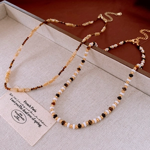 Detailed close-up of retro bohemian beaded necklaces with faux tiger eye stones and gold clasps