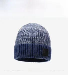 Dettaglio del berretto in maglia bicolore blu e grigio con toppa in pelle e risvolto