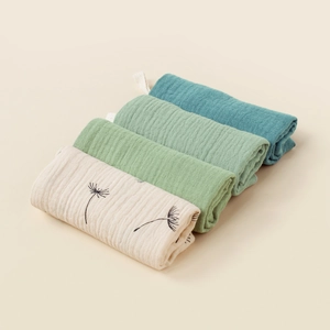Detail of 4-pack muslin baby washcloths with dandelion print and soft cotton textures