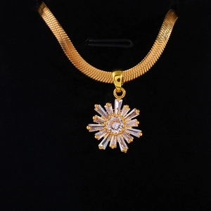 Macro shot of gold snake chain with a crystal sunflower pendant on black velvet