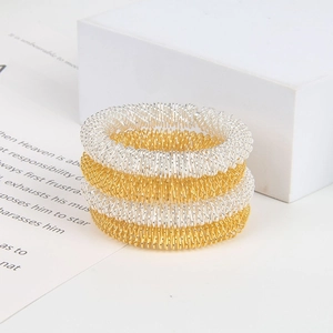 Detailed view of silver and gold spring wire massage rings on a minimalist white setup