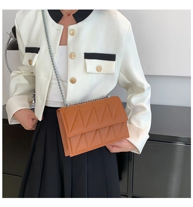 Brown quilted chain bag styled with a white jacket and black pleated skirt
