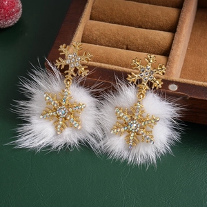 Detail of snowflake earrings with sparkling rhinestones and white pom poms on jewelry box