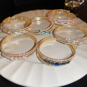Close-up of multi-layer gold bracelets with cubic zirconia and colorful gemstones