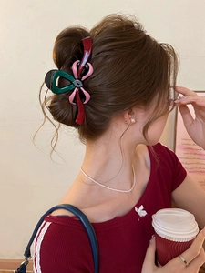 Détail d'une grande pince à cheveux nœud rose et émeraude portée par un mannequin