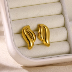 Detailed view of gold wing-shaped stud earrings in a beige jewelry display box