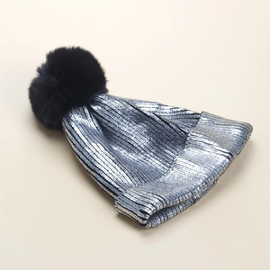 Dettaglio del cappello invernale con fibre metalliche argentate e pompon in finta pelliccia