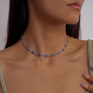 Close-up of a model wearing a silver evil eye necklace with blue and white enamel beads