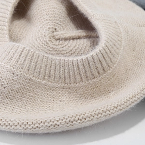 Close-up macro of the thick knit texture and ribbed edge on this warm beige beret hat
